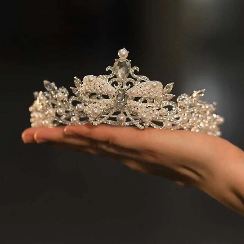 An ornate silver forehead crown featuring intricate crystal rhinestones, pearls, and a central teardrop gemstone for weddings