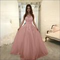 A blush pink luxury women’s fashion wedding dress with intricate floral lace and a flowing tulle skirt