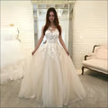 A woman wearing a luxury women’s fashion ivory wedding dress with intricate lace appliqués and a flowing tulle skirt