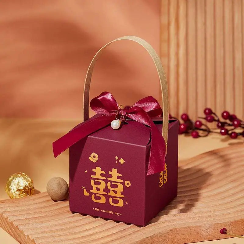 Maroon minimalist wedding candy gift box with gold handle and red satin bow featuring golden double happiness characters