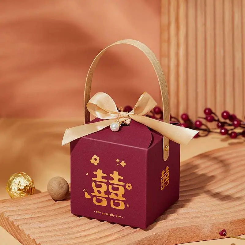 A maroon minimalist wedding candy gift box with gold handle and bow featuring golden double happiness symbols and the phrase the specially day