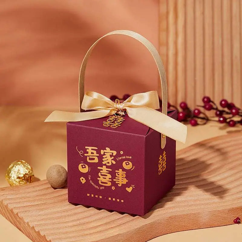 Maroon minimalist wedding candy gift box with gold satin ribbon bow handle and golden chinese decorative motifs