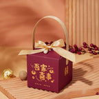 Maroon minimalist wedding candy gift box with gold foil lettering, satin ribbon bow, pearl, and gold handle