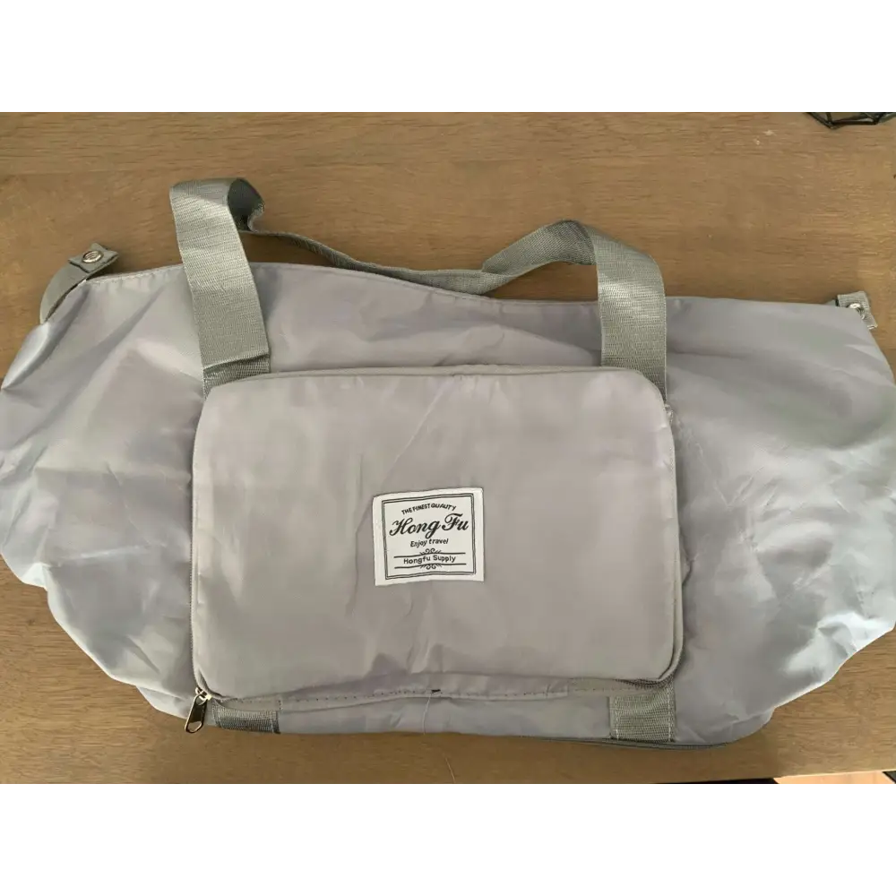 Light gray lightweight travel duffel bag with front zippered pocket and label designed for maroon wet separation sports