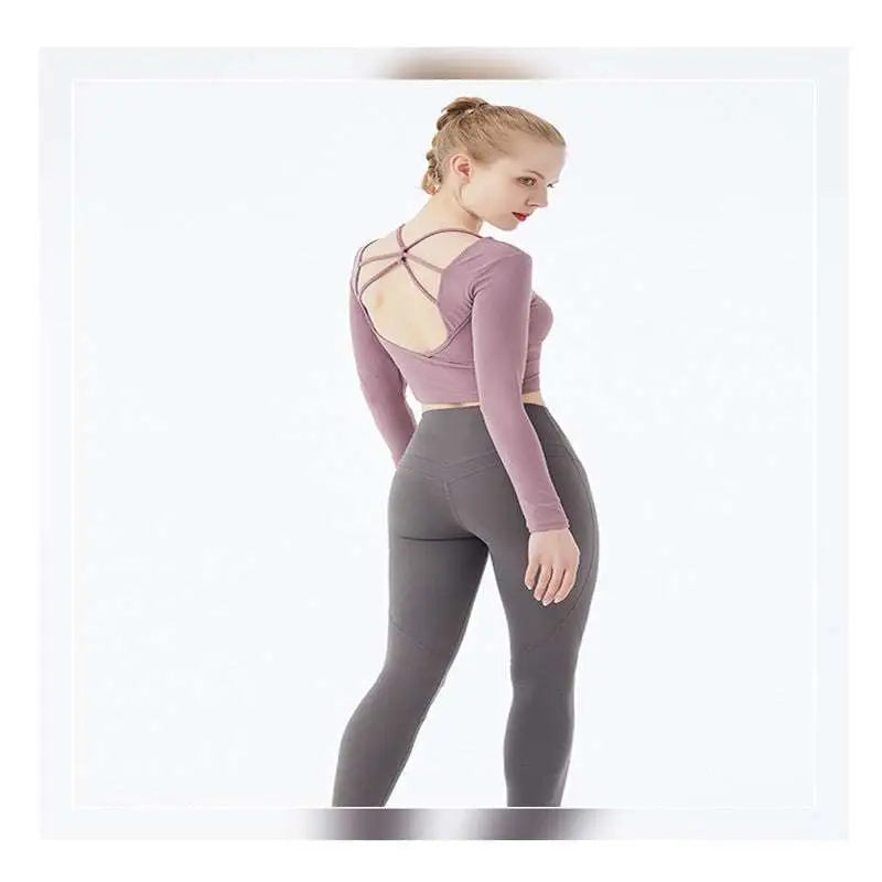 Mauve crisscross strap long sleeve yoga crop top shown from the back paired with dark gray leggings