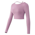 A soft mauve crisscross strap long sleeve yoga crop top with delicate shoulder straps and a sleek form-fitting design