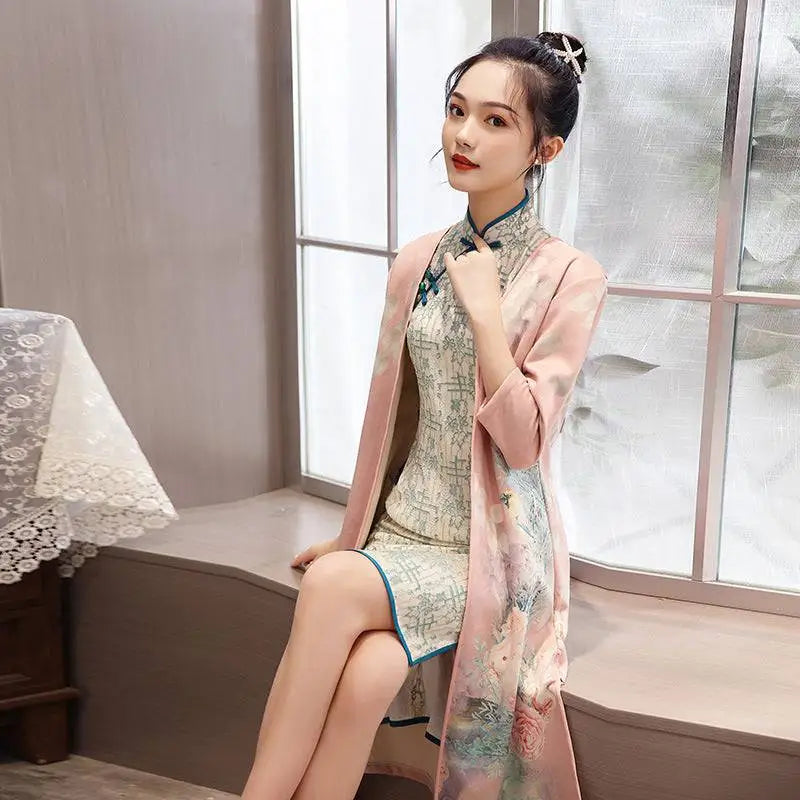 A delicate pink silk robe with floral embroidery drapes over a medium length cheongsam floral dress with teal frog closures