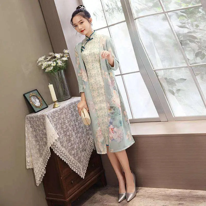 A woman wears a light mint green medium length cheongsam floral dress with teal frog closures and subtle patterned panels