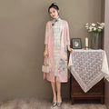 A woman wearing a medium length cheongsam floral dress set with delicate pink embroidery and teal frog closures