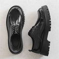 Men’s casual leather shoes in black patent leather with glossy finish, red stitching, and chunky textured soles