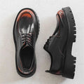 Men’s casual leather shoes in black patent leather with glossy finish, red stitching, reddish-brown toe caps, and chunky soles