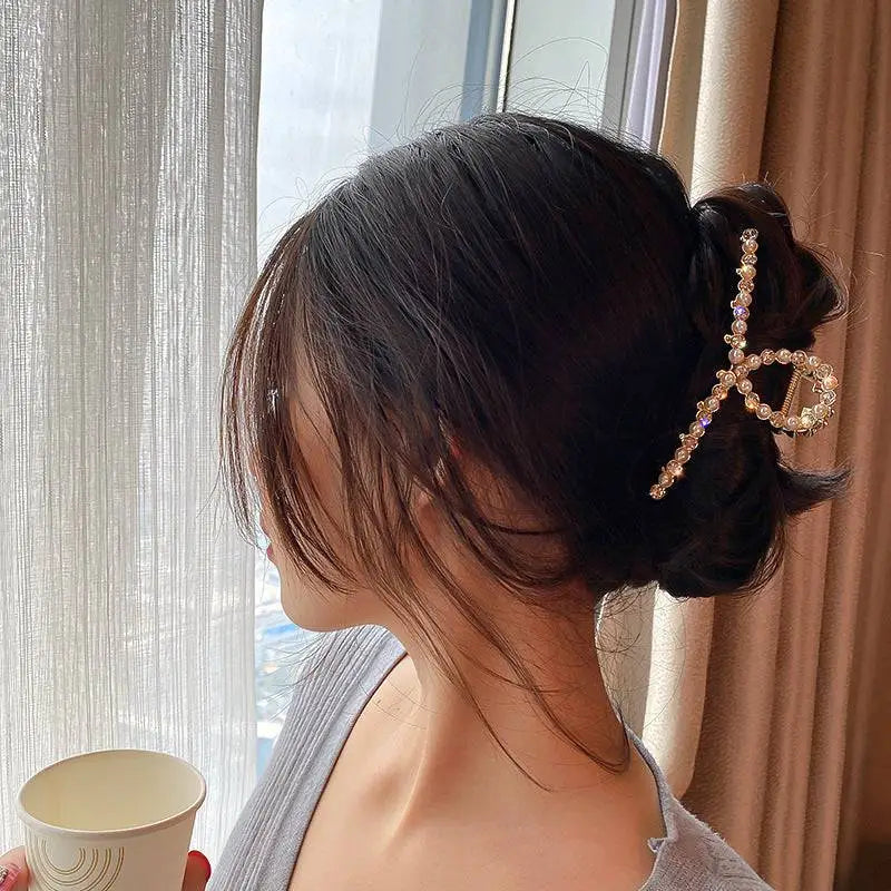 A gold shark clip designed in a delicate bow shape with clear crystals for korean elegant temperament style