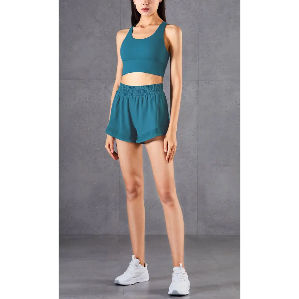 Teal two-piece athletic set with breathable fabric featuring mesh pockets fitness crop top and high-waisted shorts
