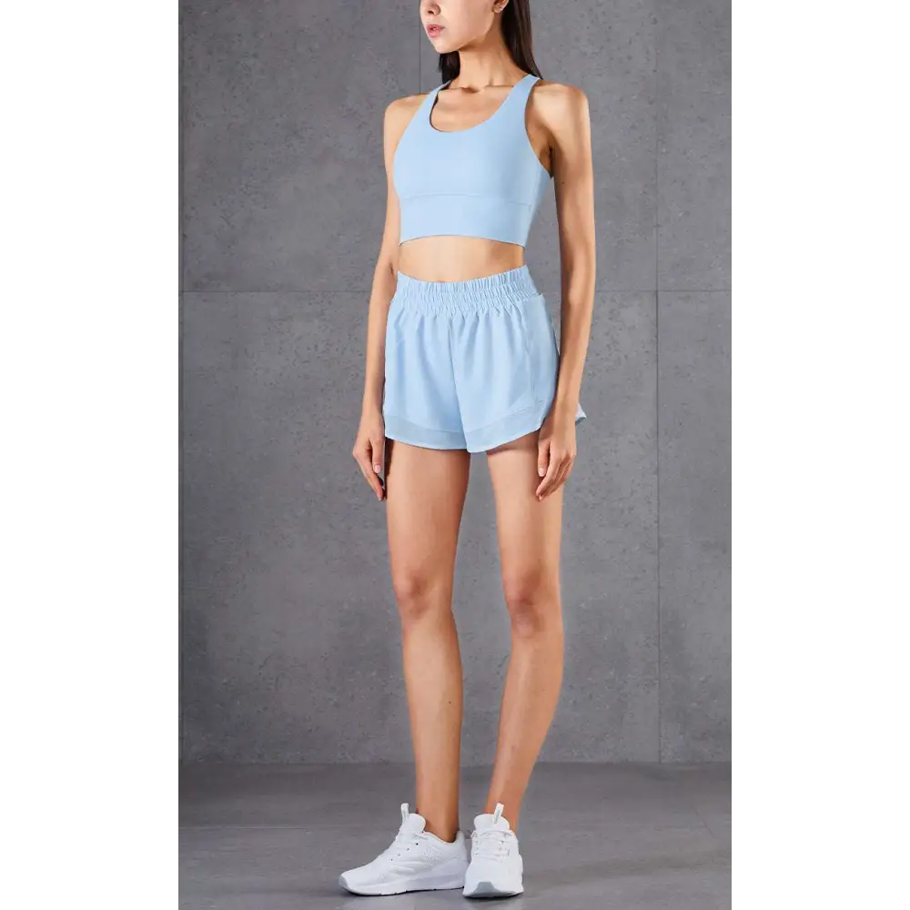 Light blue two-piece athletic set with breathable mesh pockets fitness design featuring cropped tank and high-waisted shorts