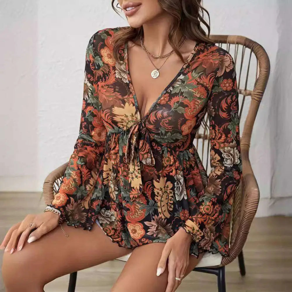 A flowing long-sleeved floral romper in earthy orange rust green with mesh printed knotted flare sleeve detail