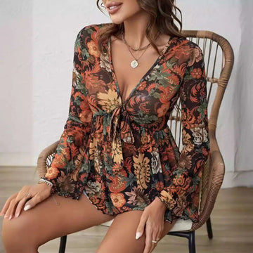 A flowing long-sleeved floral romper in earthy orange rust green with mesh printed knotted flare sleeve detail