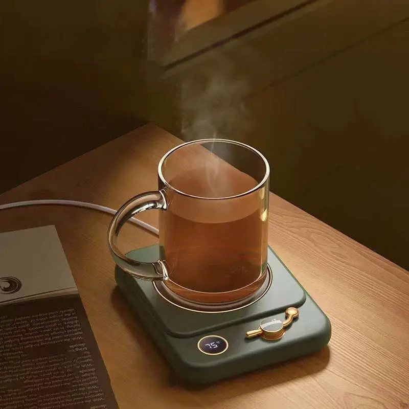 A clear glass mug with gold handle on a dark green milk heating insulation base desktop digital display warmer