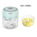 Mini electric garlic chopper in mint green with clear detachable glass bowl and stainless steel blade containing chopped food