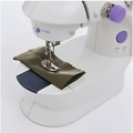 White miniature household multifunctional sewing machine with purple accents stitching olive green fabric under needle