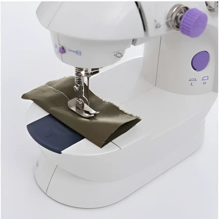 White miniature household multifunctional sewing machine with purple accents stitching olive green fabric under needle