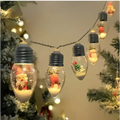Clear glass miniature scene christmas led string decorative lights with black caps featuring festive figures on white sand