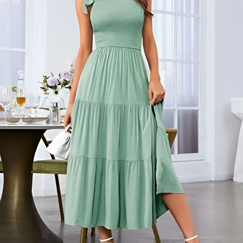 A soft mint green tiered midi dress with a fitted bodice and pleated layered hem perfect for elegant occasions