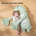 Mint green plush dinosaur baby pillow with yellow spines and white belly accents made of soft fabric