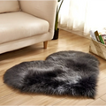 A plush heart shaped living room rug in dark gray faux fur contrasting with the mint green plush decor