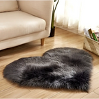 A plush heart shaped living room rug in dark gray faux fur contrasting with the mint green plush decor