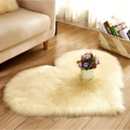 Cream-colored plush heart shaped living room rug with small floral arrangement on mint green plush background