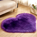 A plush heart shaped living room rug in vibrant purple with soft faux fur texture, contrasted to mint green plush options