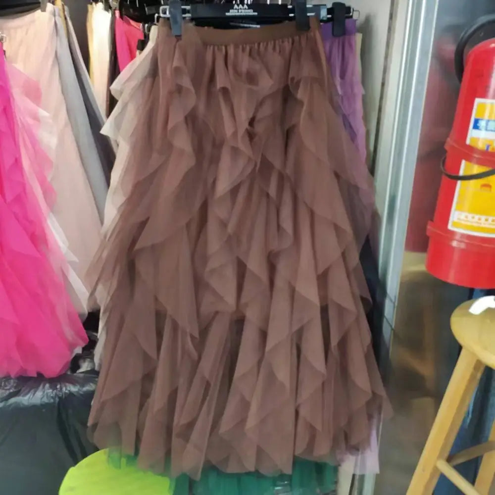 A layered brown tulle skirt with ruffled tiers highlighting mesh stitching detail on a rack for mint green tiered style