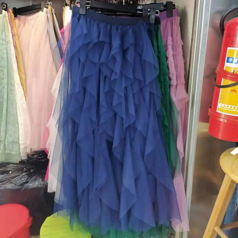 A navy blue tiered tulle skirt with multiple ruffled layers showcasing mesh stitching on a mint green tiered product rack