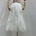 A flowing white tulle skirt with multiple ruffled layers displayed on a wooden mannequin for mint green tiered mesh stitching