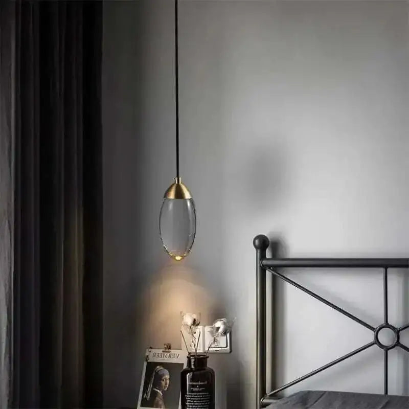 Modern brass and glass raindrop pendant lights with a gold-toned metal top and clear glass teardrop shade