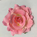 A delicate pink artificial rose with layered petals in a multicolor red roses flocking cloth headdress hairpin