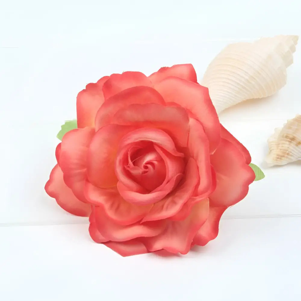 A coral-colored artificial rose with layered petals and green fabric leaves in a multicolor red roses flocking cloth headdress hairpin