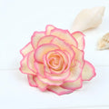 A delicate pink and cream artificial rose with layered petals on a multicolor red roses flocking cloth headdress hairpin