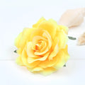A vibrant yellow artificial rose with soft petals and green leaves on a multicolor red roses flocking cloth headdress hairpin
