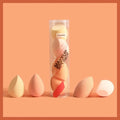 A set of pastel peach and cream hydrophilic polyurethane beauty egg makeup sponges arranged around maange packaging
