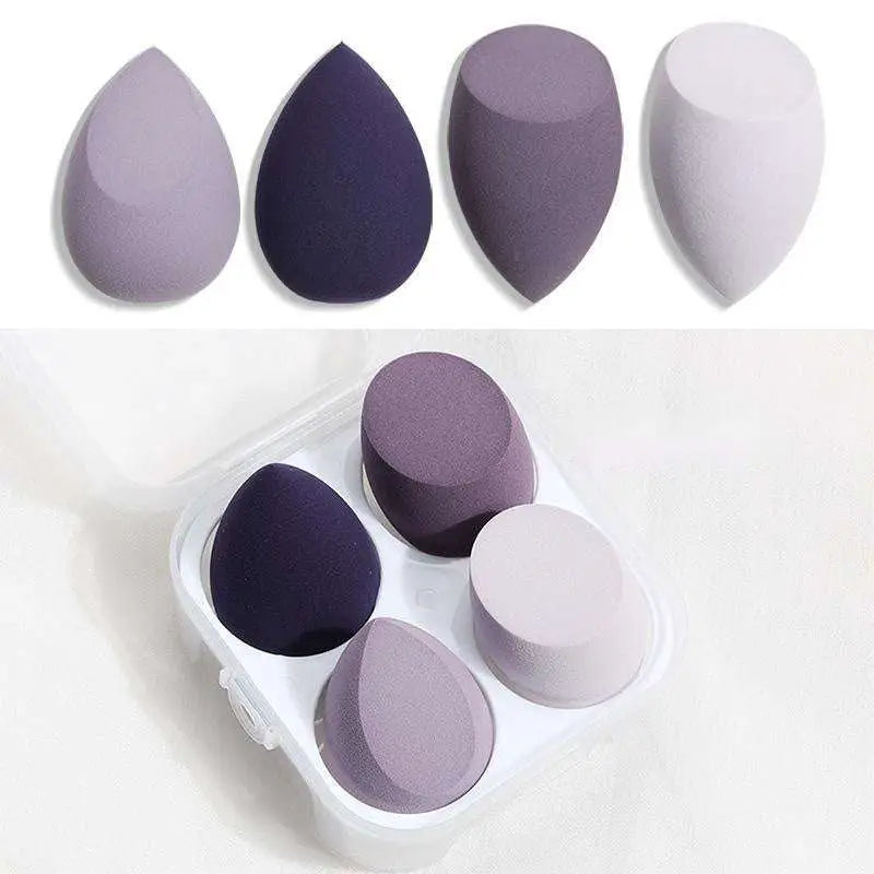 Set of four muted purple and gray hydrophilic polyurethane beauty egg makeup sponges in a clear plastic case