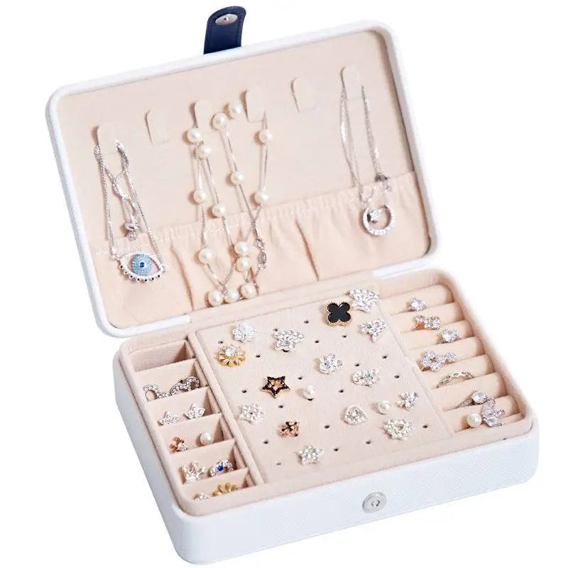 White multifunctional leather jewelry storage box with navy clasp beige compartments and built-in mirror for organizing necklaces and earrings