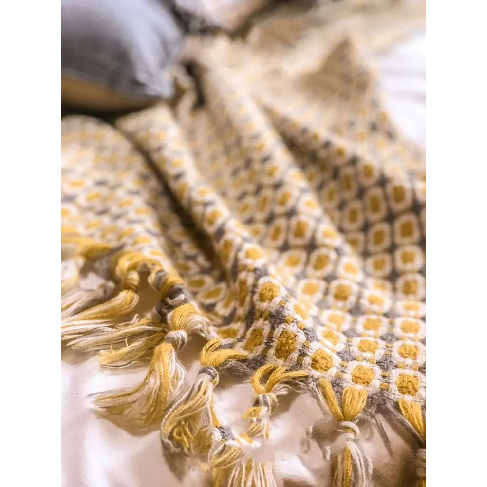 A cozy mustard yellow geometric knitted sofa blanket with soft tassels ideal for sofa cover and warmth