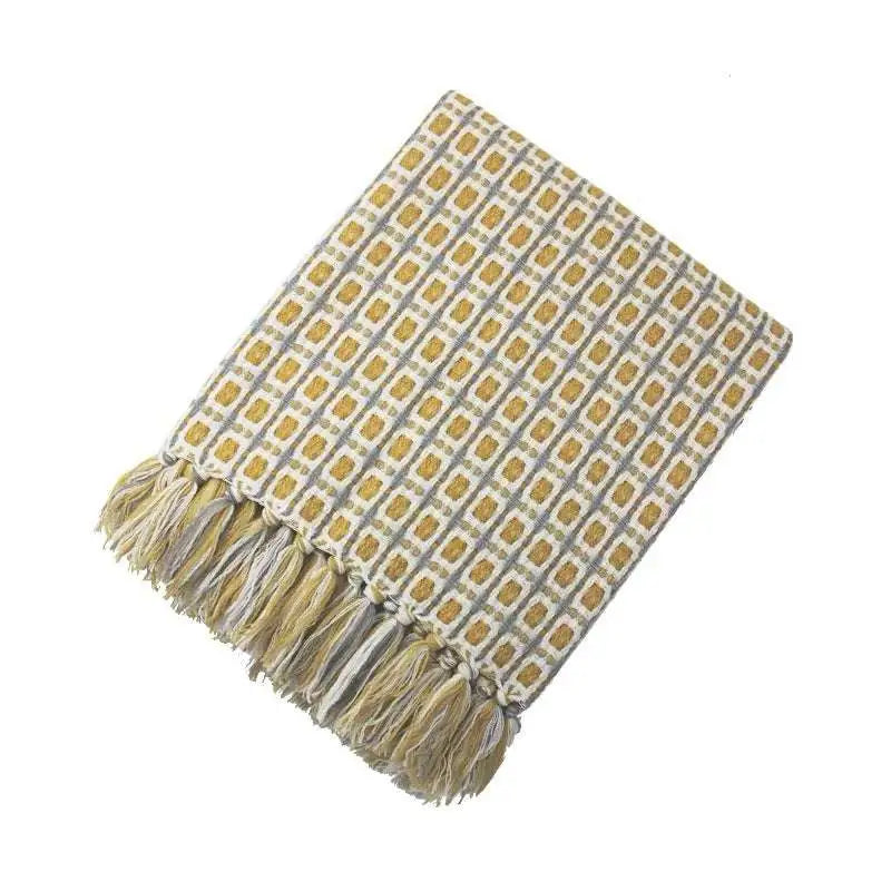 Soft woven knitted sofa blanket with mustard yellow geometric pattern and matching tassels on light gray background