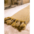 A soft mustard yellow and cream geometric knitted sofa blanket with tassels for cozy home decor