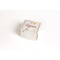 A light gray textured gift box with dried flowers and the name lynn for a natural citrus bath body skincare set