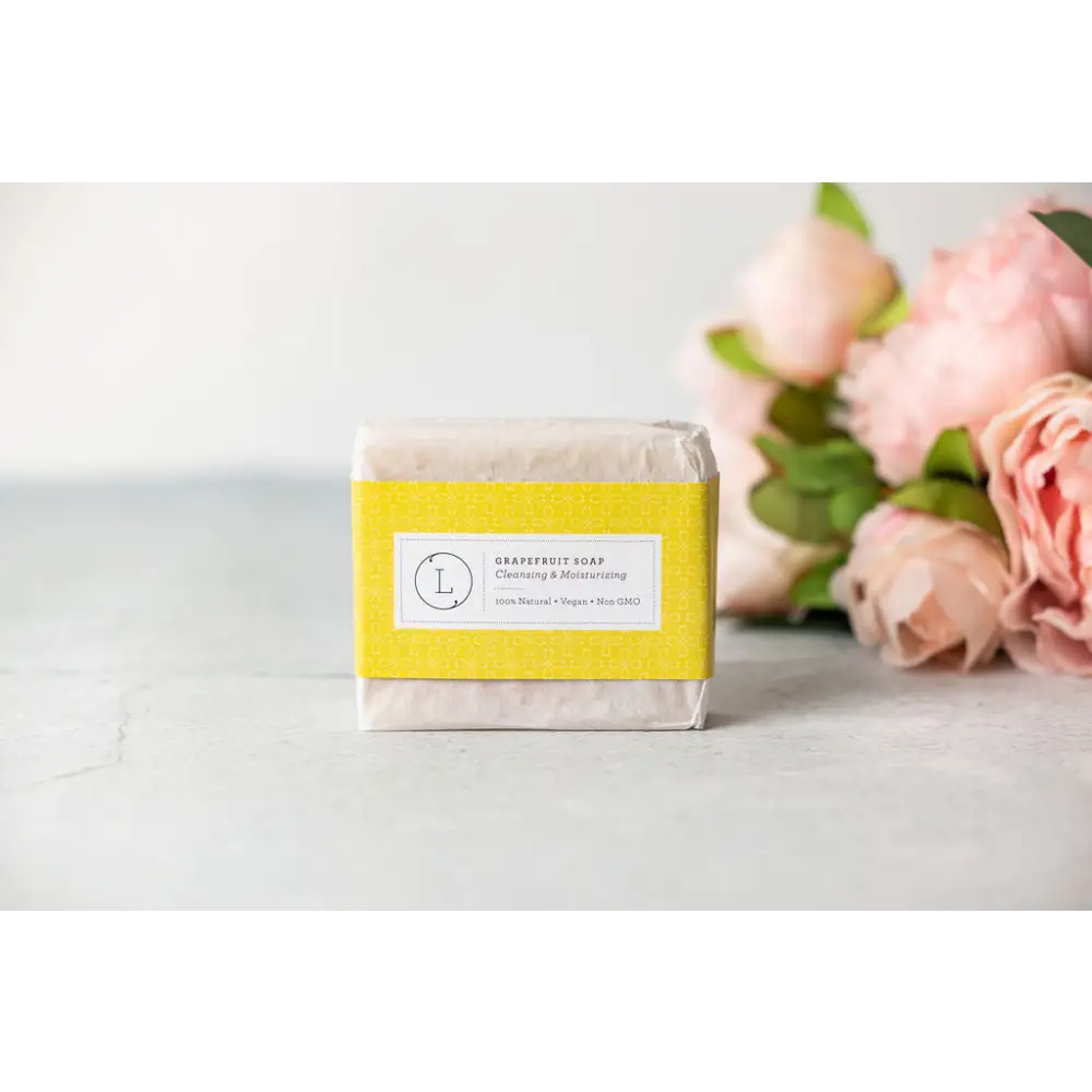 A rectangular bar of pale off-white grapefruit soap with a bright yellow label in a natural citrus bath body skincare set