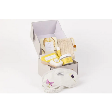 White embroidered eye mask with purple and pink floral designs in natural citrus bath body skincare set including shower steamer