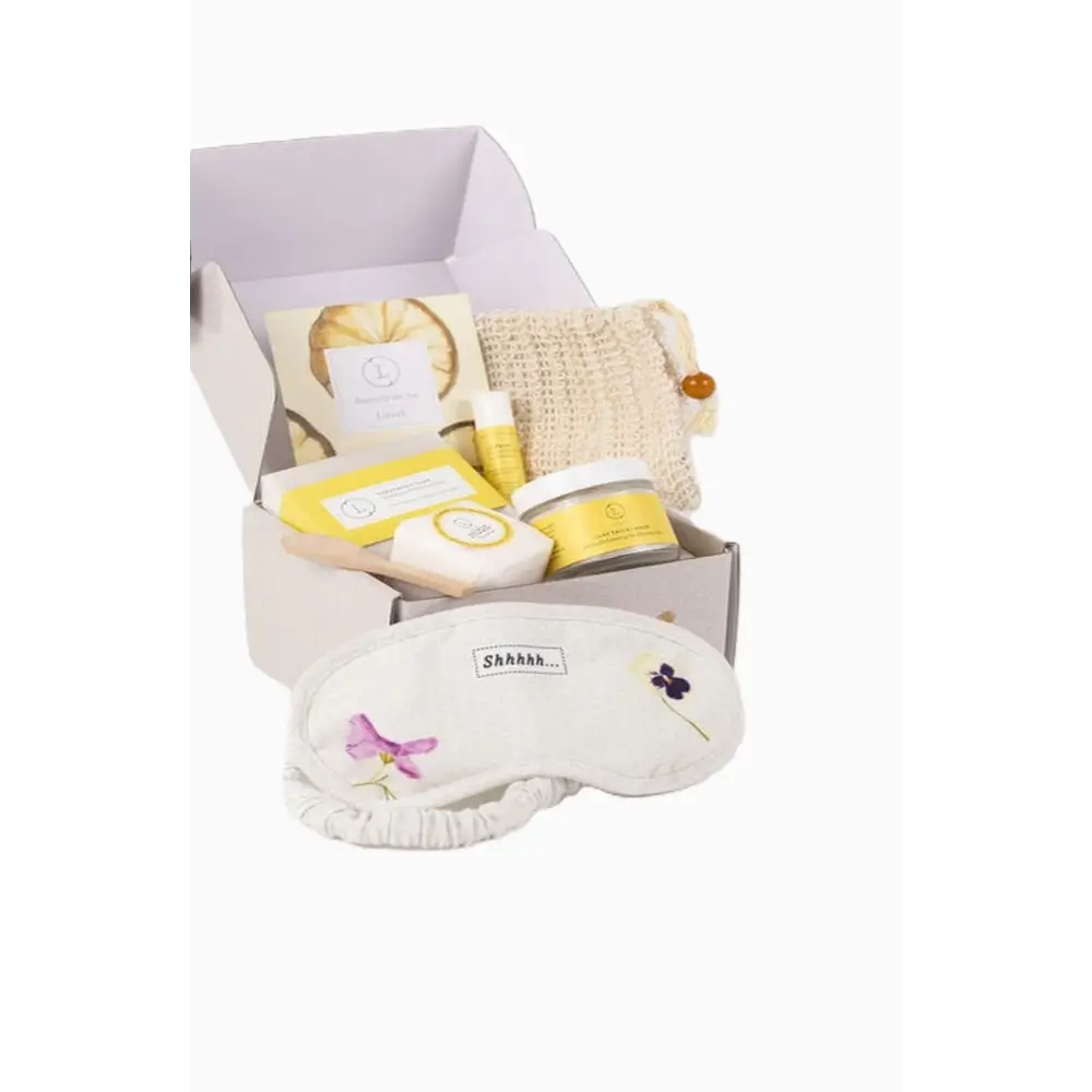 White embroidered eye mask with purple and pink floral designs and shhh label for natural citrus bath body skincare set