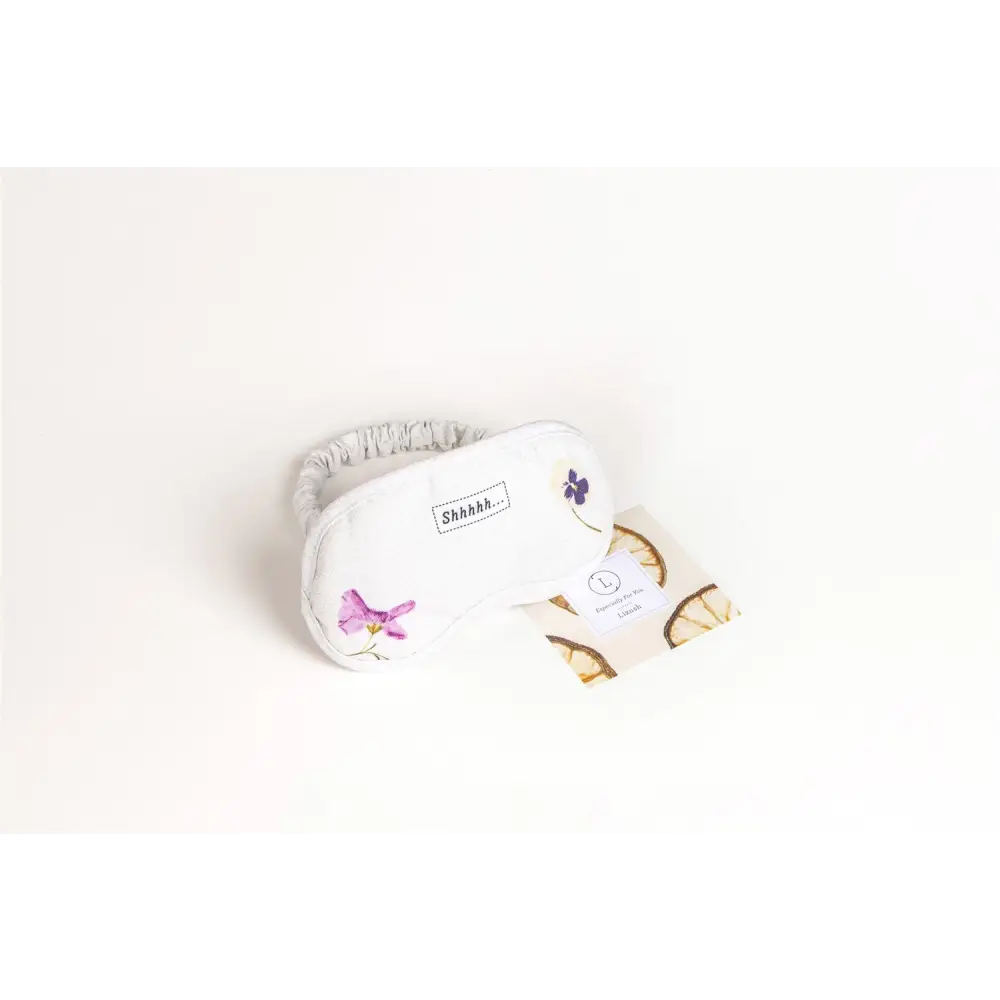 White sleep mask with embroidered purple flowers and soft elastic strap in natural citrus bath body skincare set